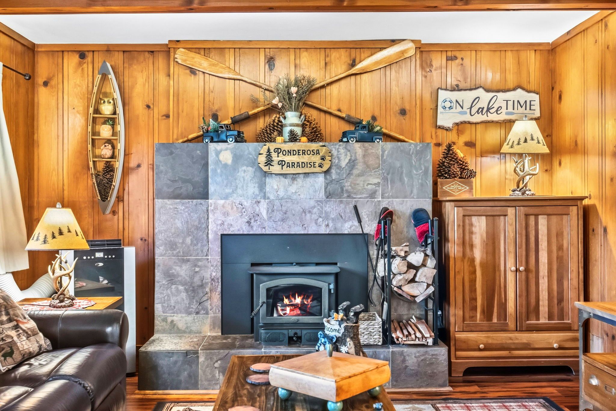 A cozy living room with a fireplace, wooden walls, a sofa, and a coffee table.