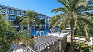 A hotel with a rooftop pool, palm trees, and a clear blue sky.