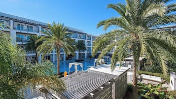 Un hotel con piscina en la azotea, palmeras y un cielo azul despejado.