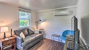 Un salon avec un canapé en cuir, une petite table d’appoint avec une lampe, un fauteuil bleu et un meuble pour la télévision.