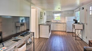 Une cuisine de taille réduite avec des meubles blancs, un four à micro-ondes encastré et un réfrigérateur.