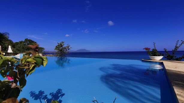 En infinitypool med fri utsikt över havet och bergen i bakgrunden.