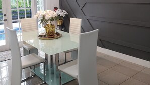 A modern dining area with a glass table, white chairs, and a decorative centerpiece.