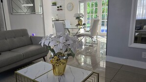 A modern living room with a grey sofa, a glass coffee table, and a vase of white flowers.