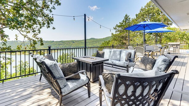 A deck with outdoor furniture, a table, and a blue umbrella. - Table Rock Lake Hideaway w/ Deck: Bring Your Boat! (Golden)