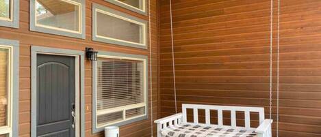 A room with a hanging swing bed, a door, and large windows.