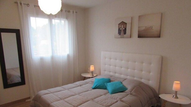 A bedroom with a large bed, two bedside tables, a mirror, and two wall-mounted artworks. - Twin house T4 for 6 persons (MESSANGES)