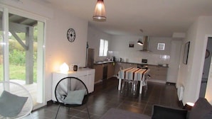 A modern kitchen with a dining area, a sofa, and a chair. - Twin house T4 for 6 persons (MESSANGES)