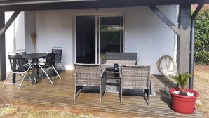 A covered patio with a table and chairs, a sliding glass door, and a potted plant. - Twin house T4 for 6 persons (MESSANGES)