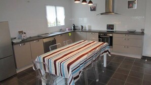 A modern kitchen with a central island, clear chairs, and a striped tablecloth. - Twin house T4 for 6 persons (MESSANGES)