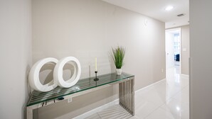A modern hallway with a glass console table, a potted plant, and a mirror. - ICON BRICKELL • CORNER TWO BEDROOM• OCEAN VIEW (Miami)