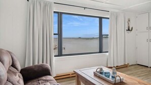 A room with a large window, a brown leather chair, a wooden table with a tray, and white cabinets. - Mille lacs Lake Beach House-Water Front-SAND-Fish (Wahkon)