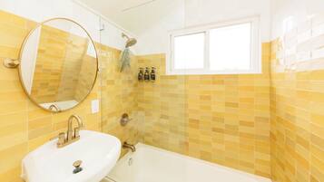 Ein Badezimmer mit Waschbecken, Spiegel und Badewanne.