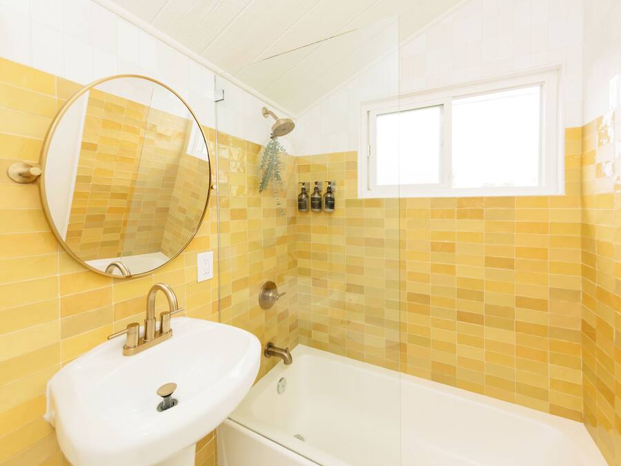 Ein Badezimmer mit Waschbecken, Spiegel und Badewanne.