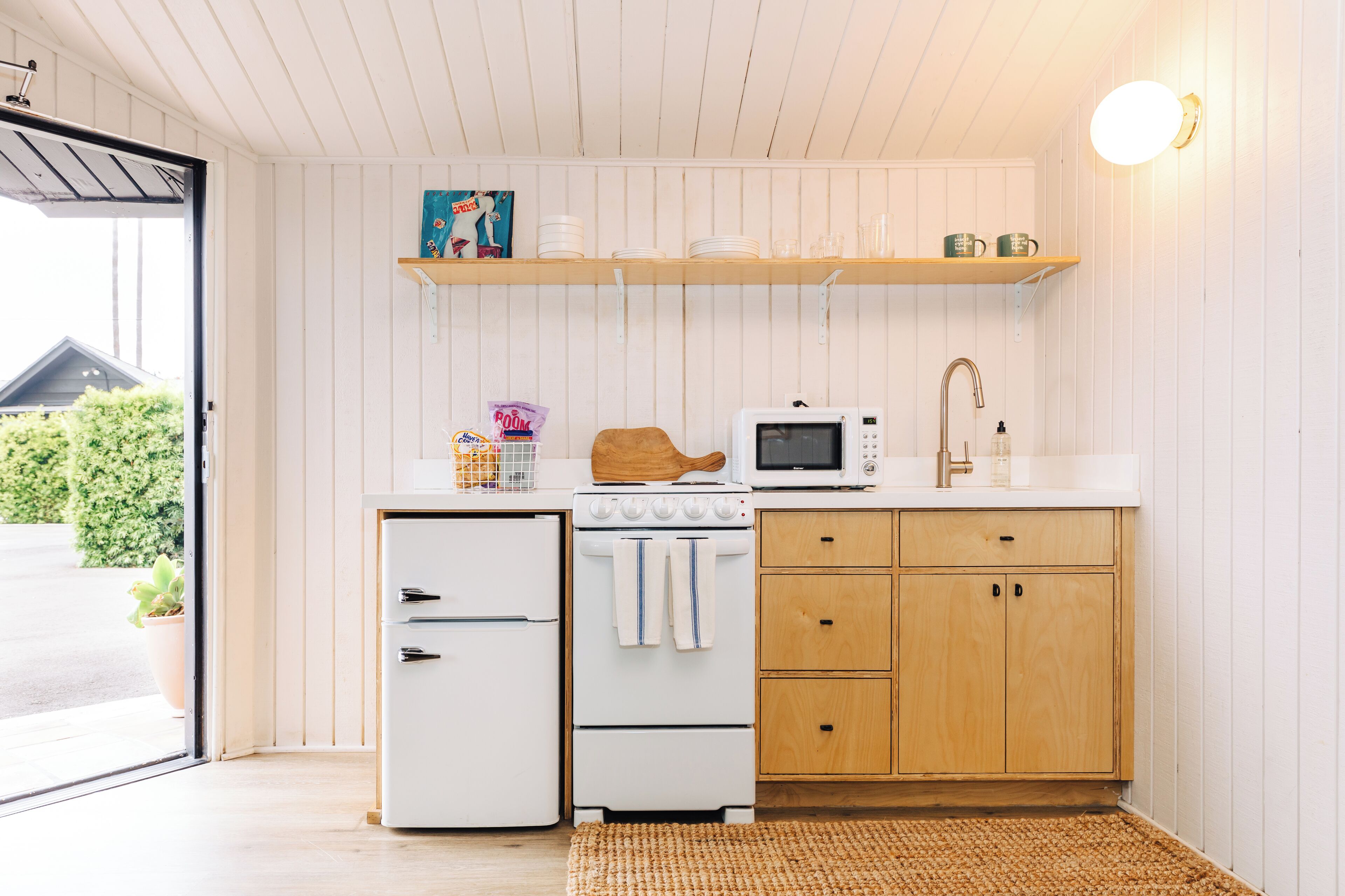 A compact kitchen with a refrigerator, stove, microwave, and wooden cabinets.