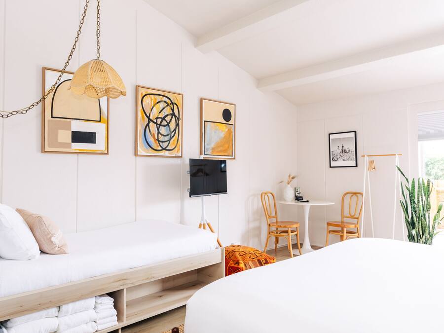 Un dormitorio moderno con cama, escritorio y silla. Hay pinturas abstractas en la pared y un televisor.