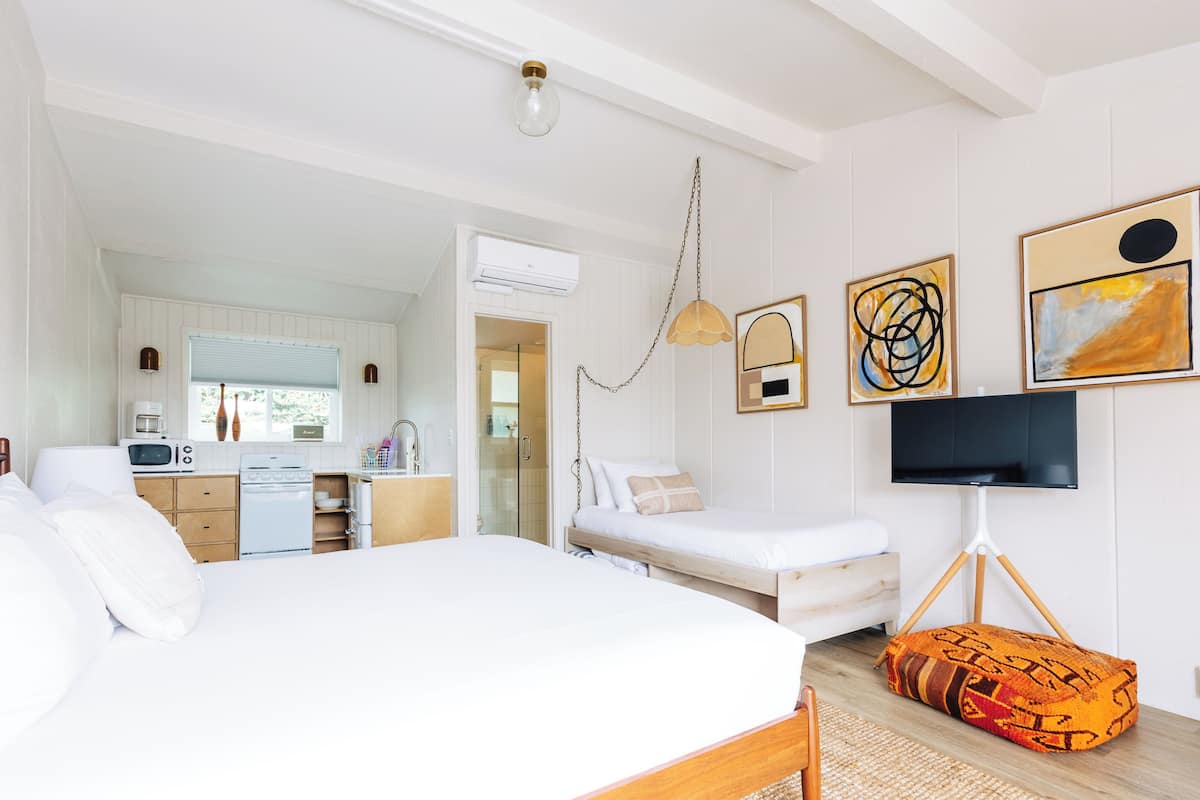 A bedroom with a bed, a TV, and artwork on the wall.
