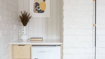 A compact kitchen with a white refrigerator, wooden cabinets, and a white brick wall.