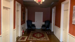 A hallway with wooden floors, two armchairs, a chandelier, and a door labeled "POWER BOUCLE". - Historic Commercial Hotel(Est.1868) "Dam Room" (Osceola)