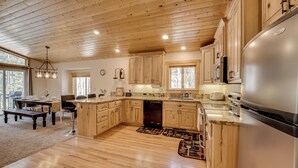 Eine geräumige Küche mit Holzausstattung, einem großen Kühlschrank und einem Essbereich mit Tisch und Stühlen.