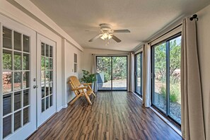 A spacious room with a wooden floor, a ceiling fan, a large sliding glass door, and a view of the outdoors. - Sedona Home w/ View, Half-Mi to Chimney Rock! (Sedona)