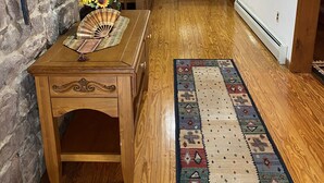 A wooden interior with a stone wall, a wooden table with a fan, and a patterned rug. - Spacious Lake Harmony Rustic Home. Month & Seasonal rates (Split rock, Lake Harmony)