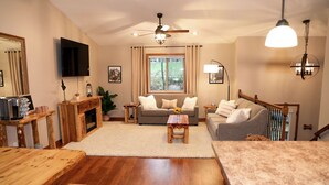 A cozy living room with a fireplace, a sofa, a coffee table, and a TV mounted on the wall. - Cozy pet-friendly home near hiking trails and Lake Vermilion (Tower)