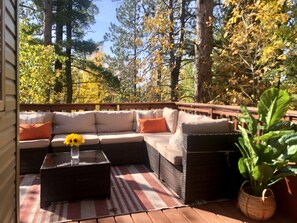A covered outdoor seating area with a sectional sofa, a coffee table, and a potted plant.