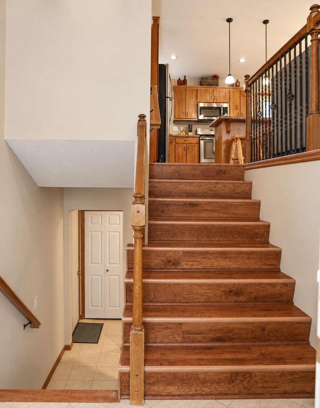 Warm wood staircase leading to a bright kitchen with rustic charm
