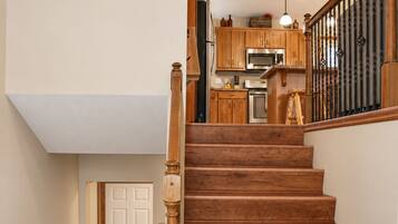 Warm wood staircase leading to a bright kitchen with rustic charm