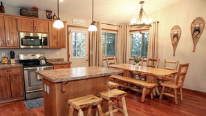 A kitchen with wooden cabinets, a central island, and a dining area with wooden chairs and benches. - Cozy pet-friendly home near hiking trails and Lake Vermilion (Tower)