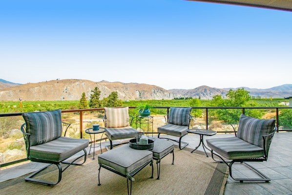 Un patio al aire libre con vistas a montañas, que incluye dos sofás, una mesita y una planta en maceta.