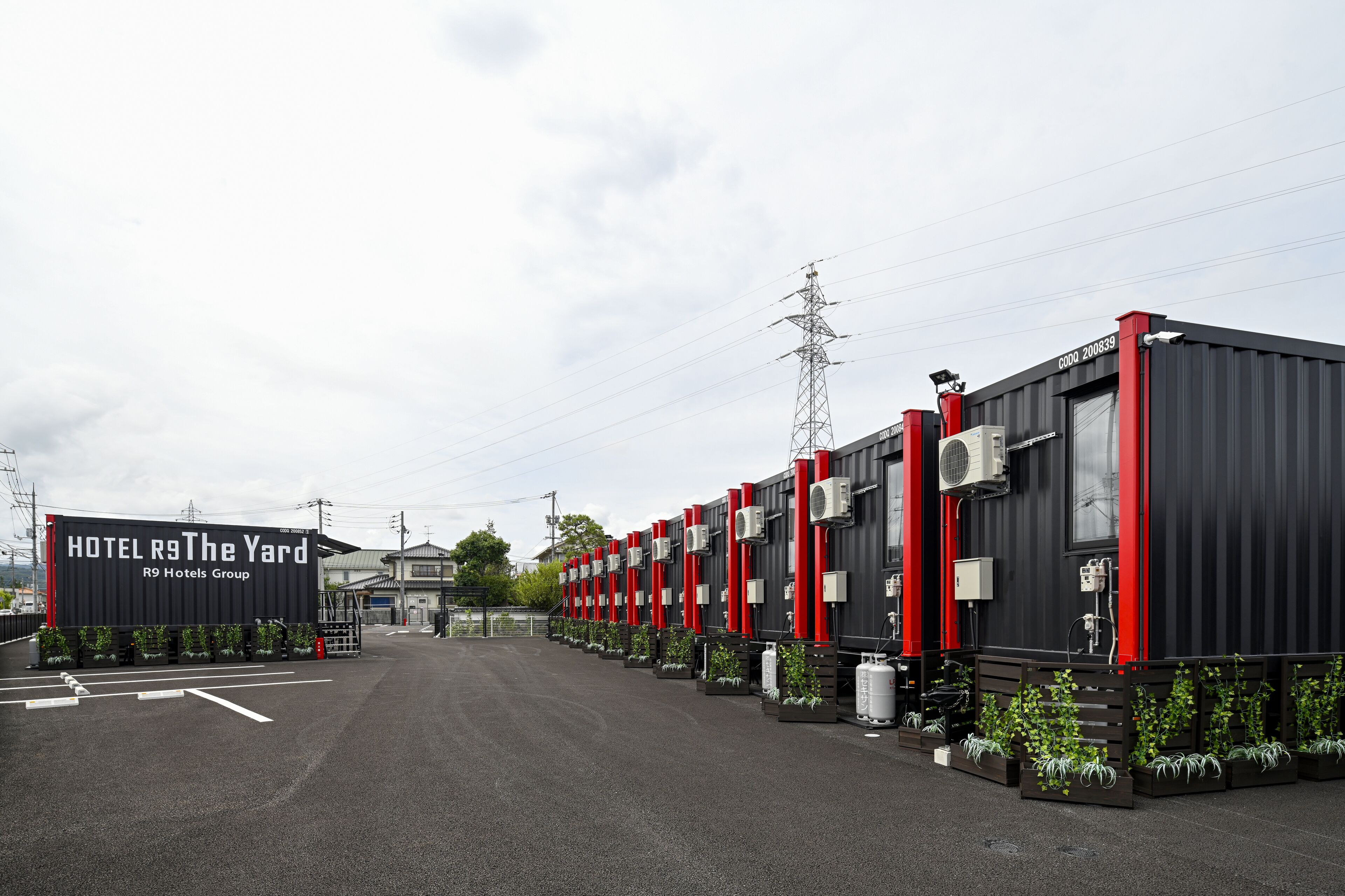 Eine Reihe schwarzer und roter, modularer Hotelzimmer mit einem Schild, auf dem „HOTEL R9 The Yard R9 Hotels Group“ steht.