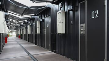 Un couloir bordé de portes numérotées, qui semblent indiquer des chambres d’hôtel, et un passage.