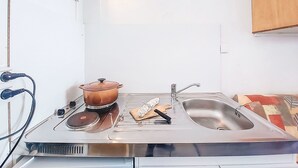 A kitchen with a stove, sink, and wooden cabinet. - Apartment Cosmos by Interhome (Le Corbier)