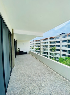 A modern apartment with a balcony, large windows, and a view of other buildings.
