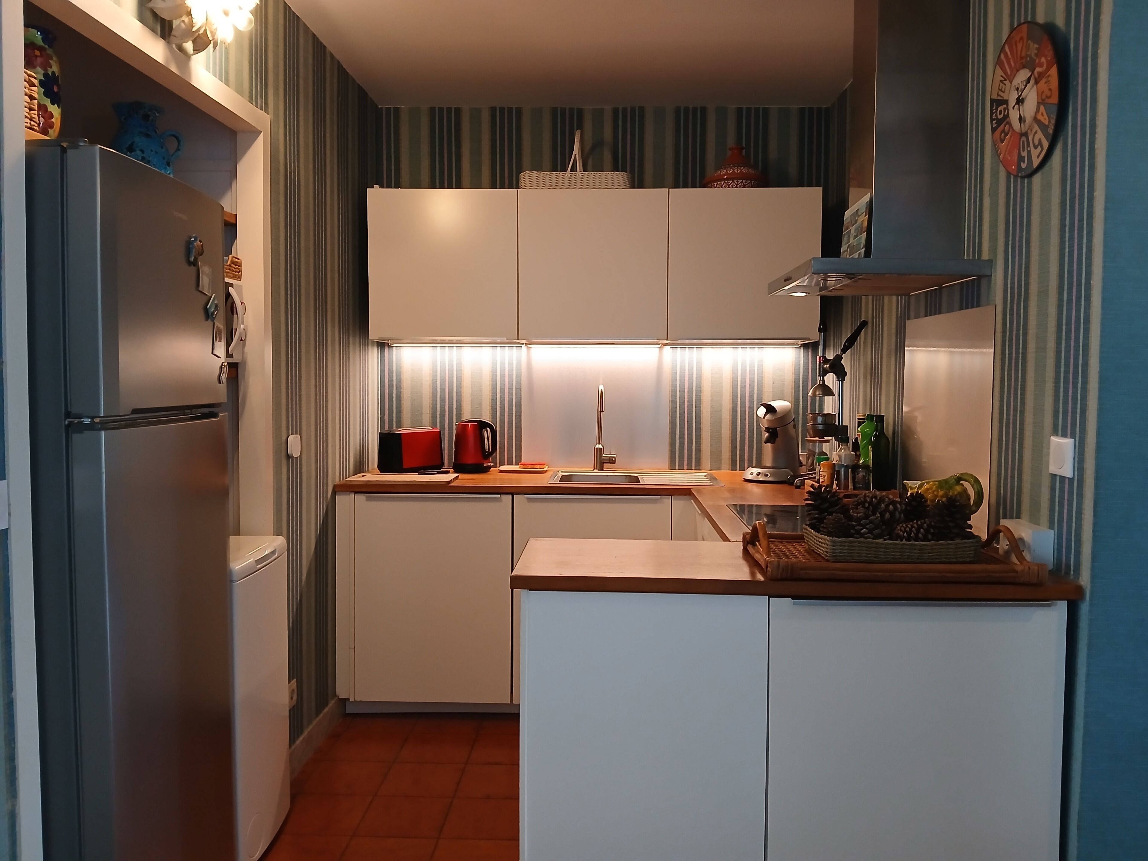 Een kleine keuken met een koelkast, een koffiezetapparaat, een broodrooster en een spoelbak.