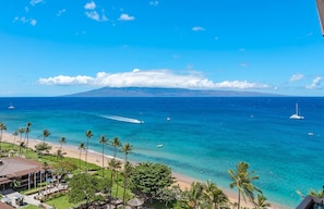 A coastal view with a clear sky, a beach, and a mountain in the distance.