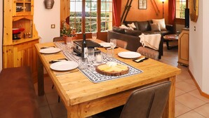 A dining area with a wooden table set for four, a wine bottle, and a candle centerpiece. - Colline 1 by Interhome (Champex)