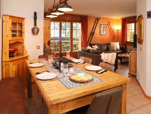 Un comedor con una mesa de madera dispuesta para cuatro personas, una botella de vino y un centro de mesa con velas.