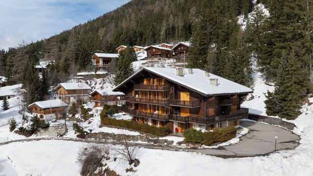 A large wooden lodge with multiple balconies, surrounded by snow-covered trees and a mountainous backdrop. - Colline 1 by Interhome (Champex)