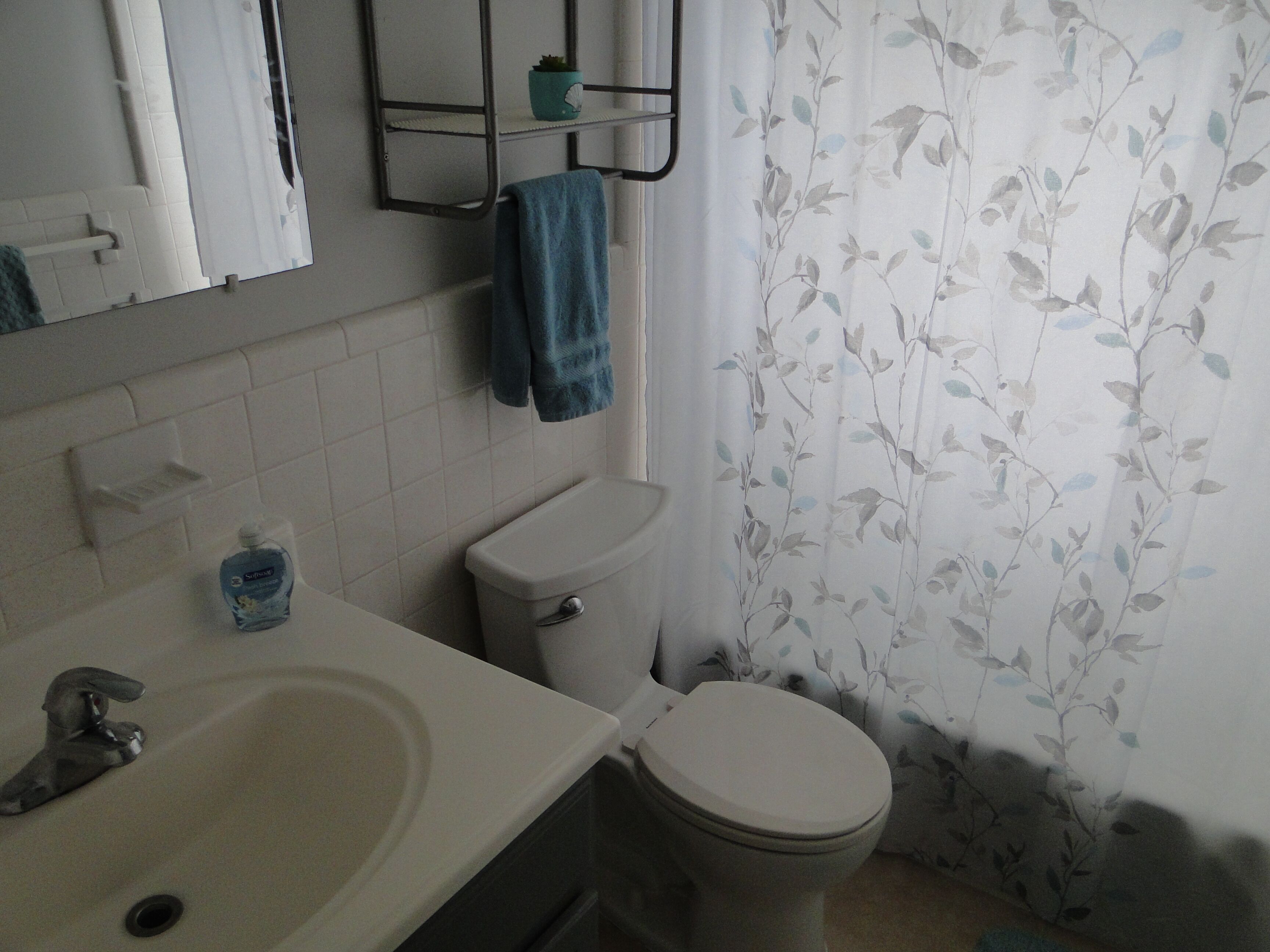 Un baño con inodoro, lavamanos y cortina de ducha con estampado floral.