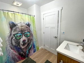 Bathroom features a shower curtain with an abstract design, a sink with a modern faucet, and a small rug.