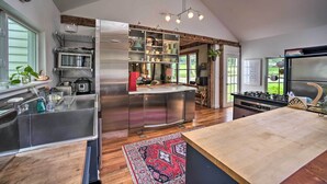Cozinha moderna com eletrodomésticos de aço inoxidável, ilha de madeira e uma janela grande.