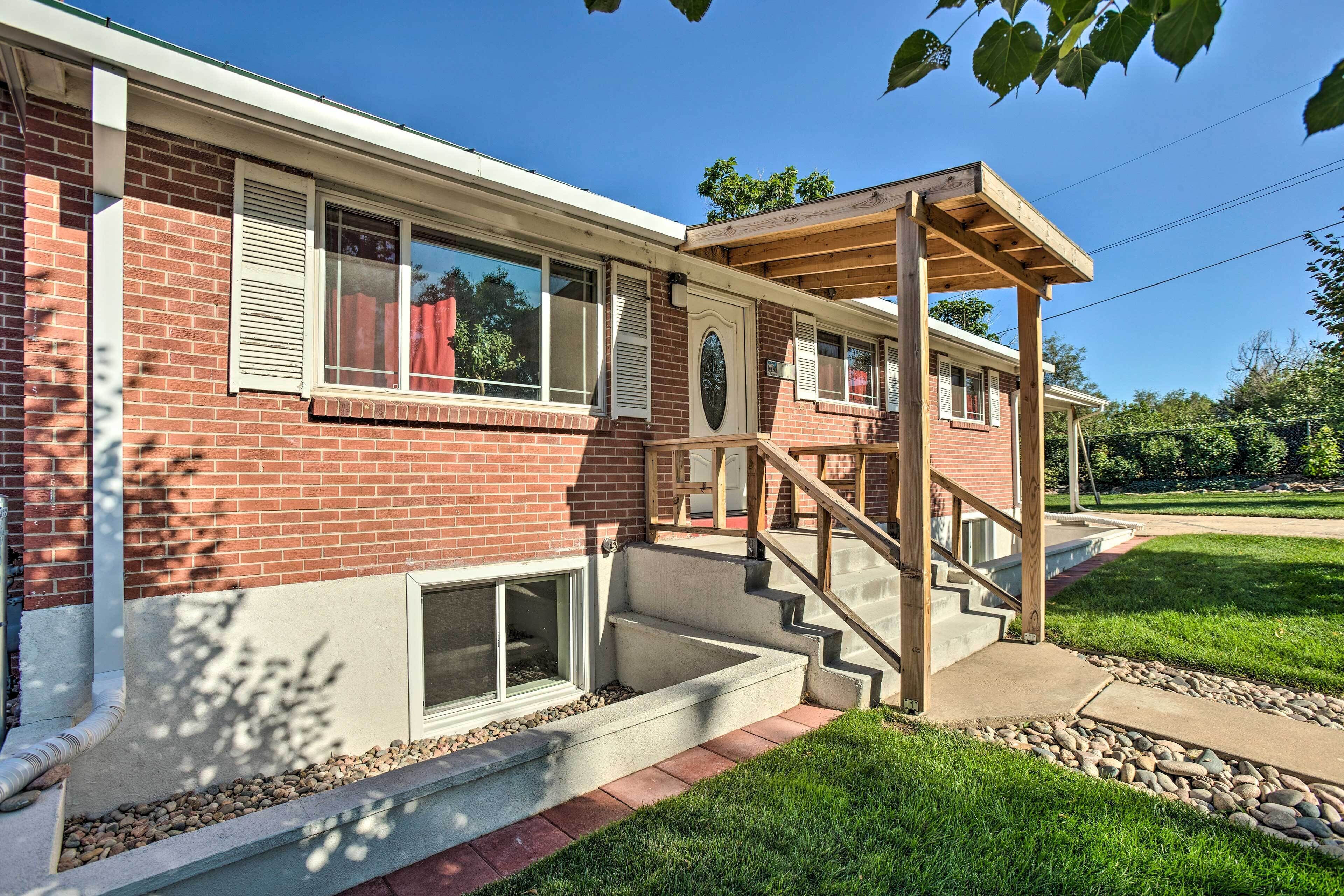 Une maison à deux étages, construite en briques, avec un porche couvert et un escalier en béton menant à l’entrée.