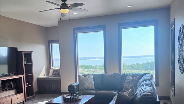 A living room with a sectional sofa, a coffee table, a TV stand, and a ceiling fan.
