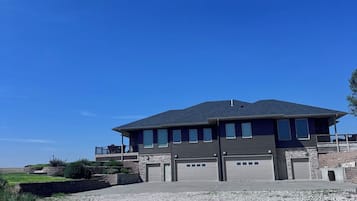 A two-story building with a flat roof, a balcony on the upper floor, and a garage with two doors.