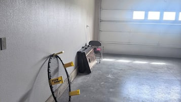 Un garaje con una raqueta de tenis apoyada en la pared, un enchufe y una puerta de garaje.