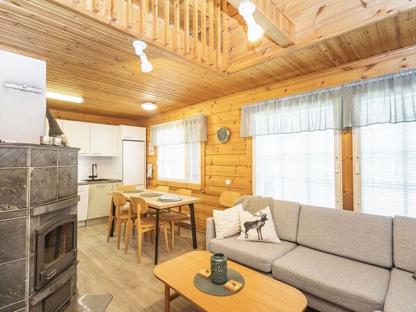 L’intérieur d’une cabane comprend un coin repas, un canapé, une cheminée et des murs en bois.