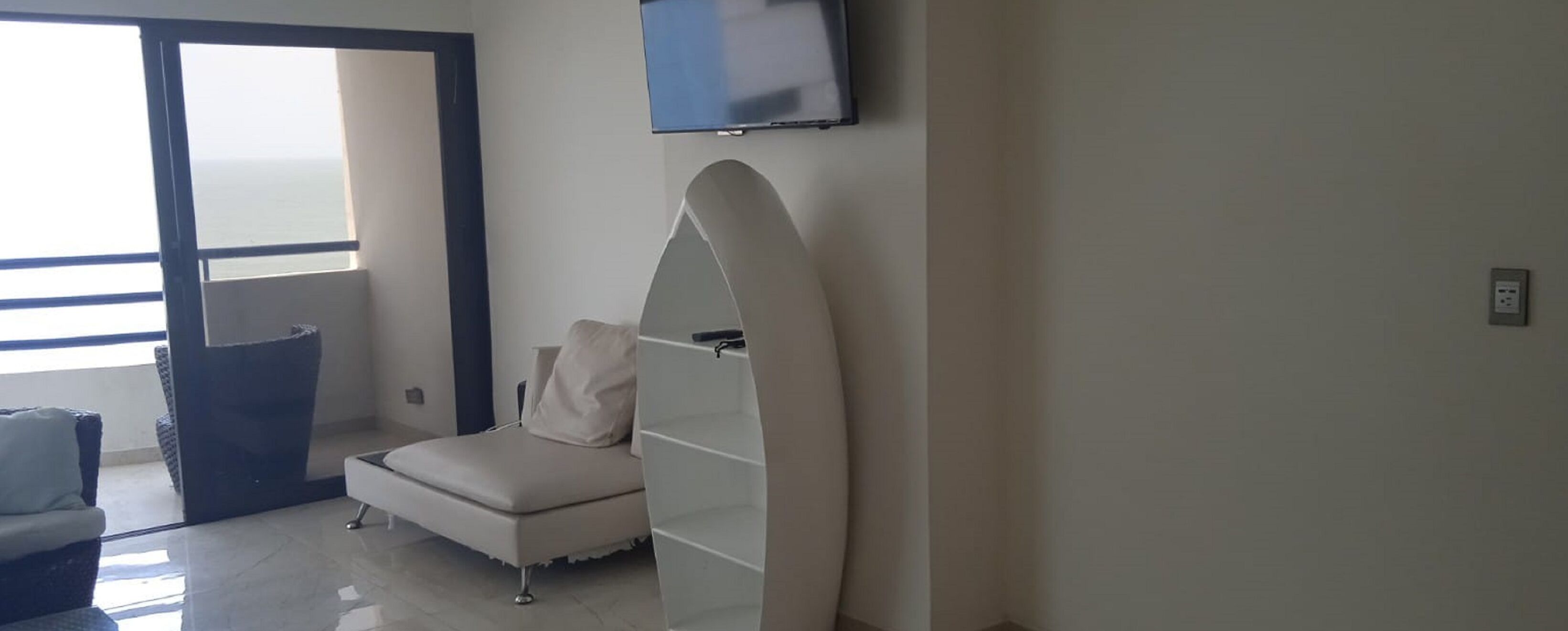 Ein modernes Hotelzimmer mit Bett, Wand-Fernseher und großem Fenster mit Meerblick.